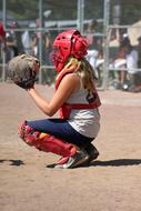 Side view of a softball catcher girl, on the sand, in summer