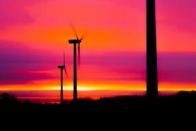 Silhouettes of the wind power plant, at colorful and beautiful sunrise in the sky