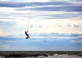 Person, doing kitesurfing on the beach of the North Sea, at beautiful and colorful sunset, among the clouds