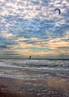 Kitesurfer, above the beautiful landscape, with the beach of the North Sea, at beautiful and colorful sunset, among the clouds