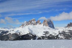 Beautiful landscape of the snowy Sella Ronde mountains in Canazei, Italy, at blue sky with clouds on background