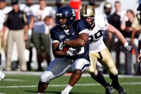 American football player running with the ball across the field