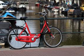 red Bicycle parked at railing of bridge, netherlands, amsterdam