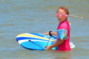 little girl with surfboard in water