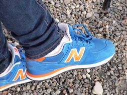 Close-up of the beautiful, blue, orange and white New Balance shoes, on the legs, on the colorful stones