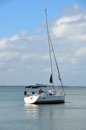 Beautiful, white sailboat on the water, at blue sky with white clouds on background