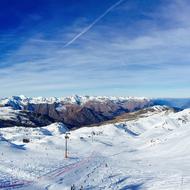 Beautiful landscape of the snowy mountains, under the blue sky with clouds and contrail