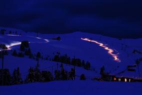 Beautiful landscape of the snowy mountains, with the trees and house, with the lights, at the night