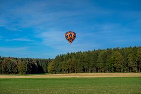 hot air balloon flying over green forest