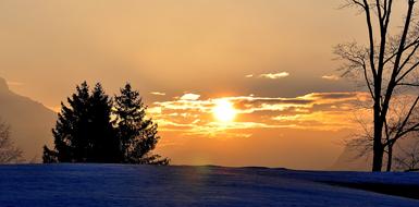 Beautiful landscape of the snowy mountains, with the trees, at beautiful and colorful sunrise, in the sky, with the clouds