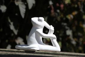 figurine of a frog in a yoga pose on a blurred background