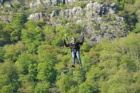 paragliding over green trees
