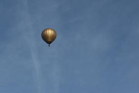 Shiny, gold hoy air balloon, flying under the blue sky, with white clouds