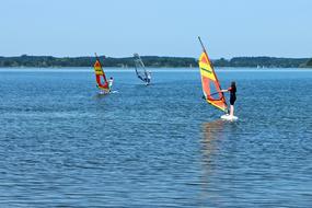 People on the colorful wind surfing boats, on the beautiful water with ripple