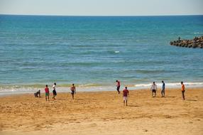 people playing soccer on the beach