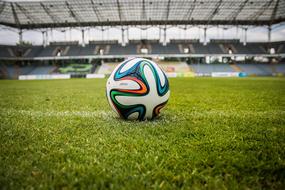 Colorful football, on the beautiful, green grass football stadium, with the tribunes