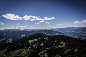 Beautiful landscape of the green mountains, with the plants, in light, under the blue sky with clouds, in South Tyrol, Italy