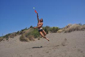 guy jumping on the beach on a sunny day