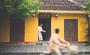 a man on a bicycle rides near the house