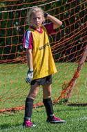 a boy in a football uniform stands near the gate