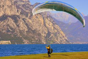 Person, doing paragliding on the beautiful and colorful shore of the Garda Lake, with the mountains, in Italy