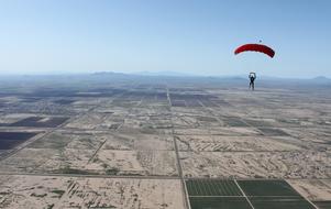 Person, doing skydiving above the beautiful and colorful desert
