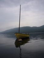 Boat, among the beautiful lake, near the mountains on the shore, under the cloudy sky