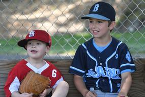 Boys in baseball uniform, watching baseball game, on the field with the fence