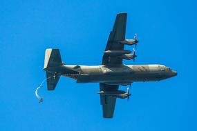 Person, jumping with the parachute, out of the flying aircraft, under the blue sky