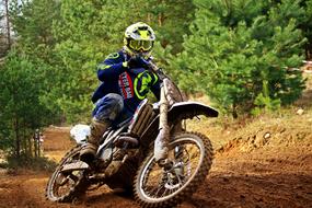 Rider in colorful equipment, on the motorcycle, on the motocross race, among the green plants