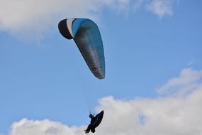 paraglider with blue black wing in the sky