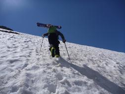 Person, climbing on the beautiful, snowy mountain in light, at blue sky on background