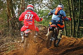motorcyclists ride through mud during motocross