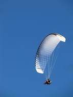 Glider on the parachute, in light, under the blue sky