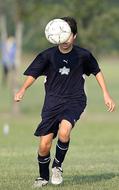 football player in a black uniform with a white ball on a blurred background