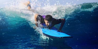 man lies on a surfboard on the water