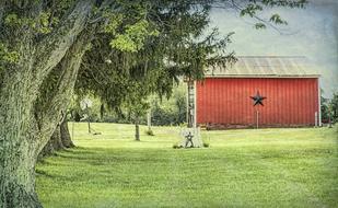 Beautiful, red barn with the star, among the green field with trees in Ohio, USA