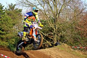 Colorful person riding on the motorcycle Enduro competition, among the colorful and beautiful forest