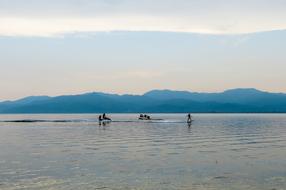 People in the beautiful sea with ripple, at background with mountains and colorful and beautiful sunset