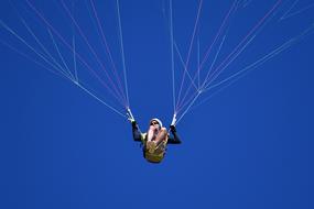 Person doing paragliding in the beautiful, blue sky