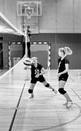 Black and white photo of the volleyball girl players, playing on the court indoors