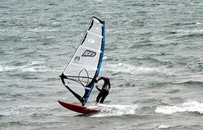 Windsurfer on the colorful boat, on the sea with waves