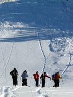 People doing backcountry skiing on the beautiful, snowy mountains in sunlight and shadows, in the winter