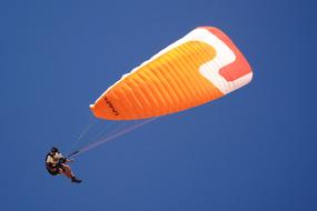 Person, flying on the bright, colorful parachute in South Africa, under the blue sky