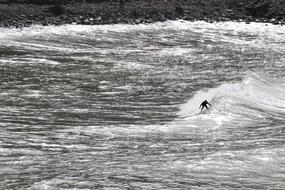 distant view of surfer in waves in monochrome