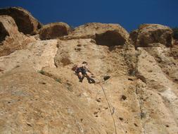 climbing a sheer cliff on a sunny day