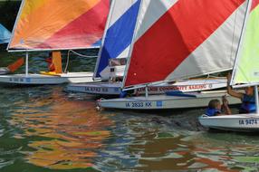 People on the colorful sailboats, on the water with ripple