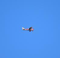 red and yellow plane high in the blue sky