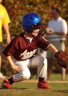 Baseball player of the Little League, on the green field in sunlight, near the colorful tres