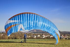 Hang glider with colorful parachute, on the colorful and beautiful field with plants